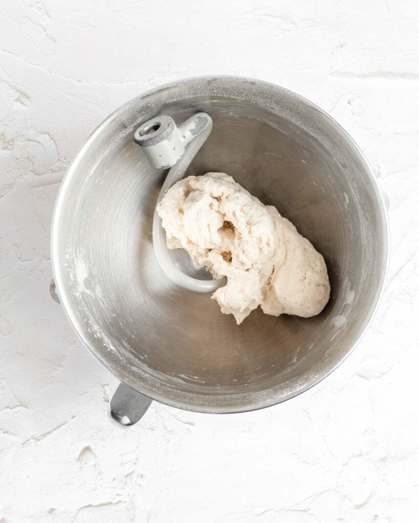 bagel dough after mixing but before lumping has pulled clean from the sides of the bowl but is lumpy and shaggy and slightly torn.