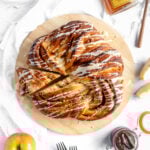 an overhead shot of a round babka on a wooden board drizzled with honey icing