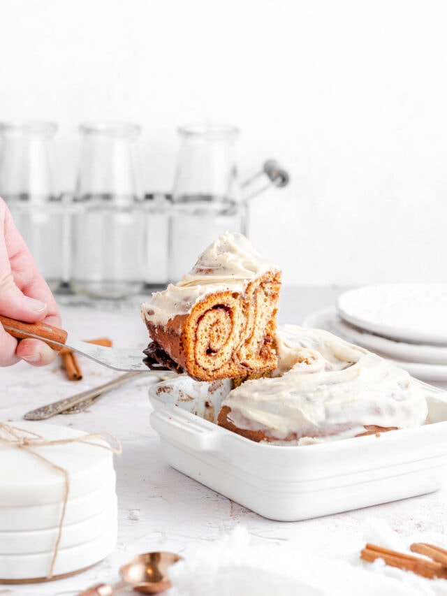 a side view of a slice of cinnamon roll being lifted from the small baking dish