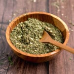 a close up of a dried basil pesto blend in a wooden bowl