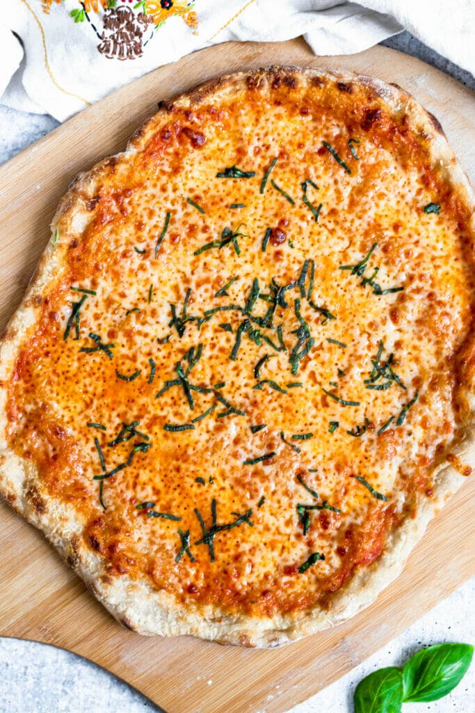 an overhead shot of a cheese pizza topped with chiffonade basil