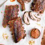 overhead shot of ribs on parchment paper with a small bowl of applesauce