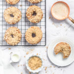 an overhead shot of crumb cake doughnuts on a cooling rack with a bowl of crumbs nearby