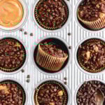 an overhead shot of a muffin tin with 8 chocolate muffins and one filled with peanut butter