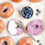 a blueberry bagel sliced open slathered in cream cheese