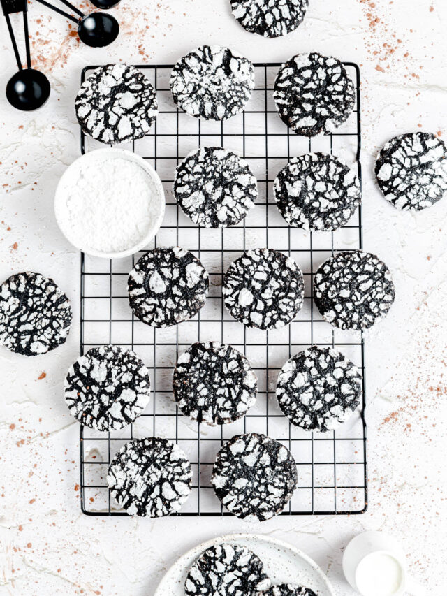 cookies on a cooling rack with a small bowl of powdered sugar