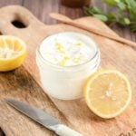 lemon yogurt sauce in a small glass jar. half a lemon rests against it.