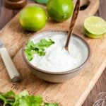 a small bowl of cilantro lime yogurt sauce with a wooden spoon in it
