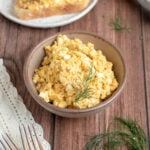 egg salad in a small brown bowl garnished with dill.