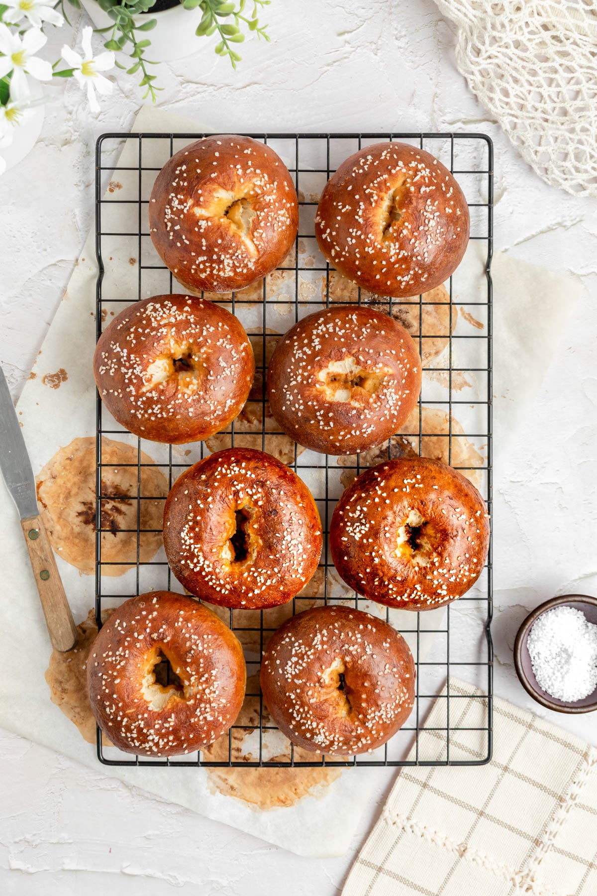 an overhead shot of 8 pretzel bagels on a black wire cooling rack