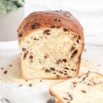 a loaf of chocolate chip brioche bread with one slice cut off in front of it