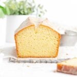 a loaf of glazed vanilla pound cake with a slice cut off the front showing the crumb inside.