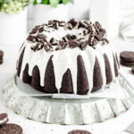 a dark chocolate bundt cake with white icing drips and crushed oreos around the top of it.