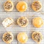 cream cheese stuffed bagel bombs on a cooling rack. one has been split open.