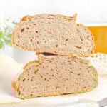 a loaf of whole wheat bread cut in half, the halves are stacked on top of each other with the crumb facing out.