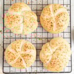 four kaiser rolls on a black wire cooling rack.
