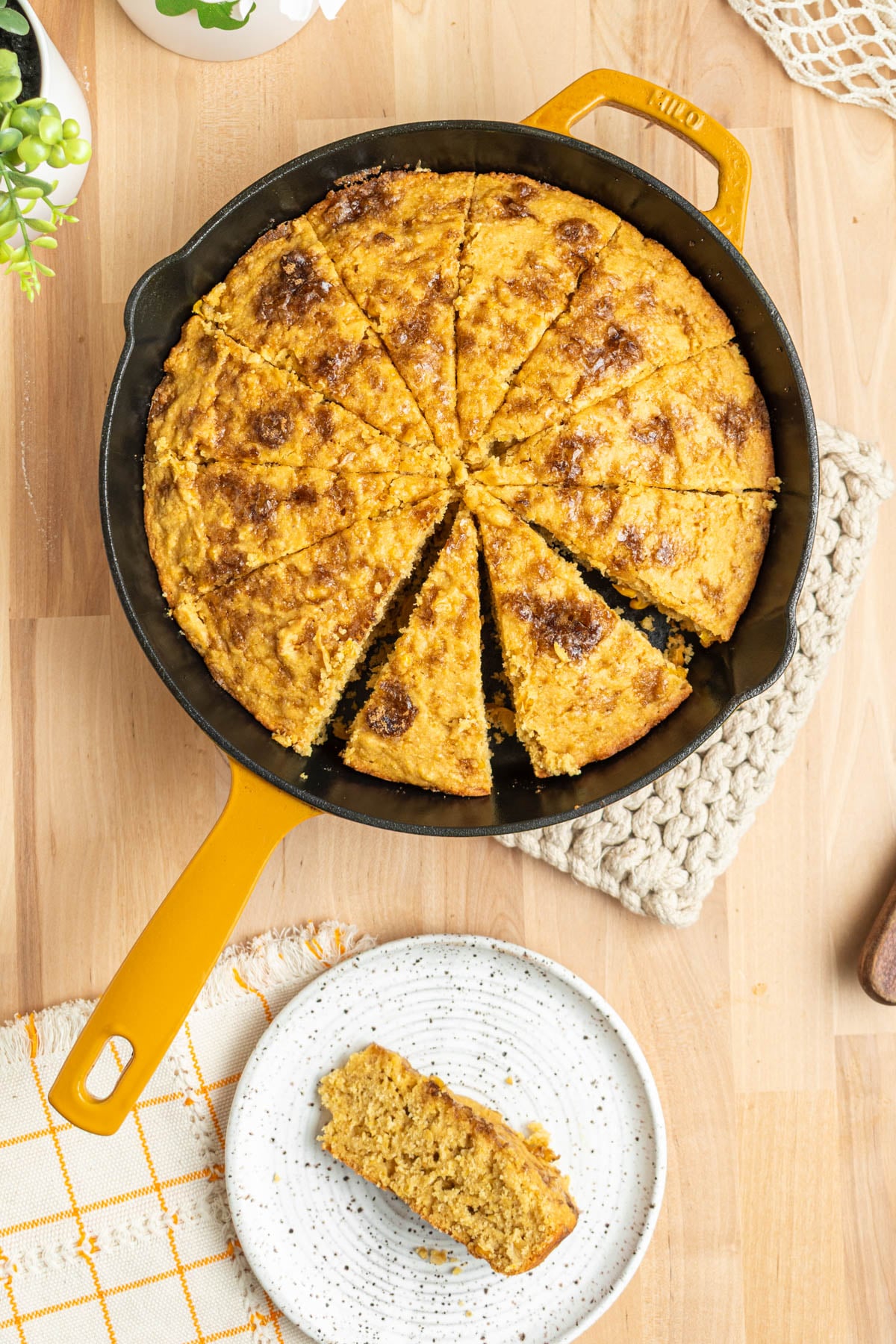 cornbread cut into 12 wedges in a cast iron skillet on a butcher block surface