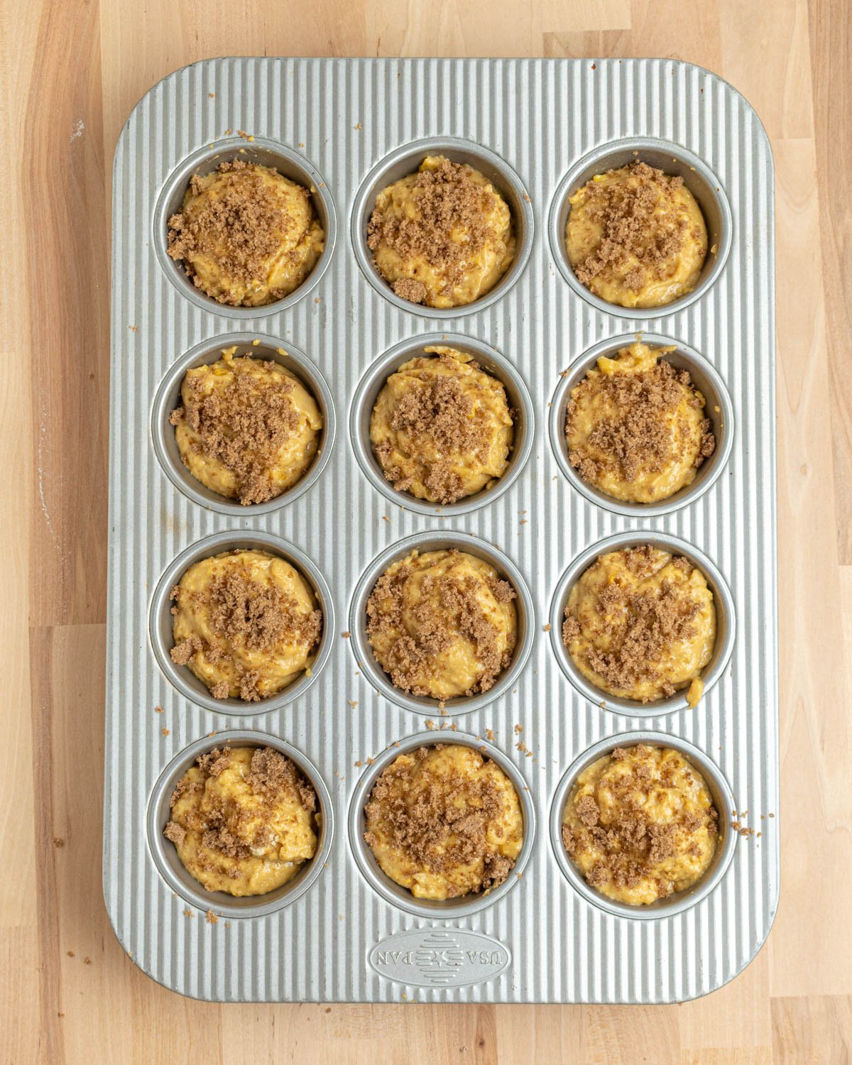 12 corn muffins topped with brown sugar before baking.