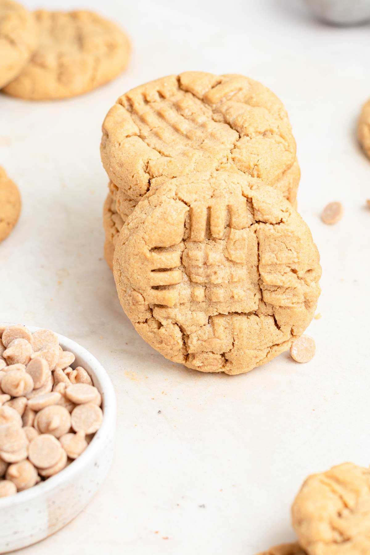 A stack of peanut butter cookies with one cookie leaning against the side of the stack.