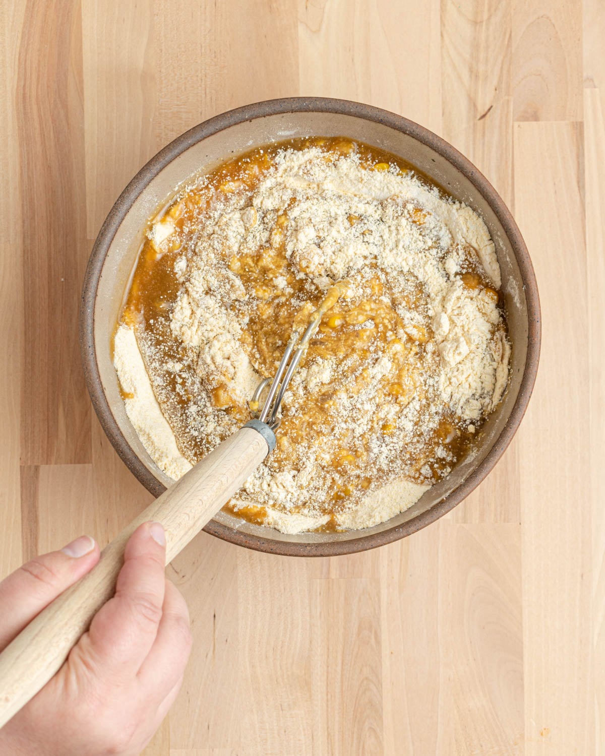 Using a dough whisk to combine the wet ingredients and the dry ingredients.