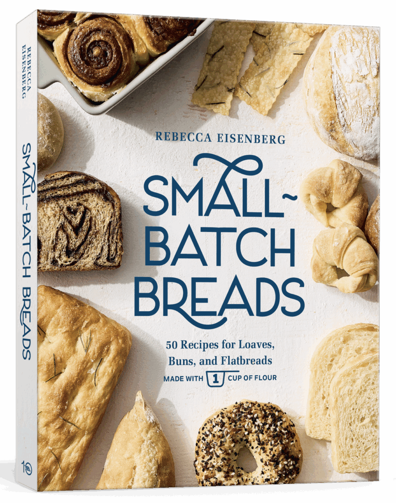 A cookbook titled Small-Batch Breads by Rebecca Eisenberg, featuring various loaves, buns, flatbreads, and rolls on the cover. The book promises 50 recipes made with one cup of flour.